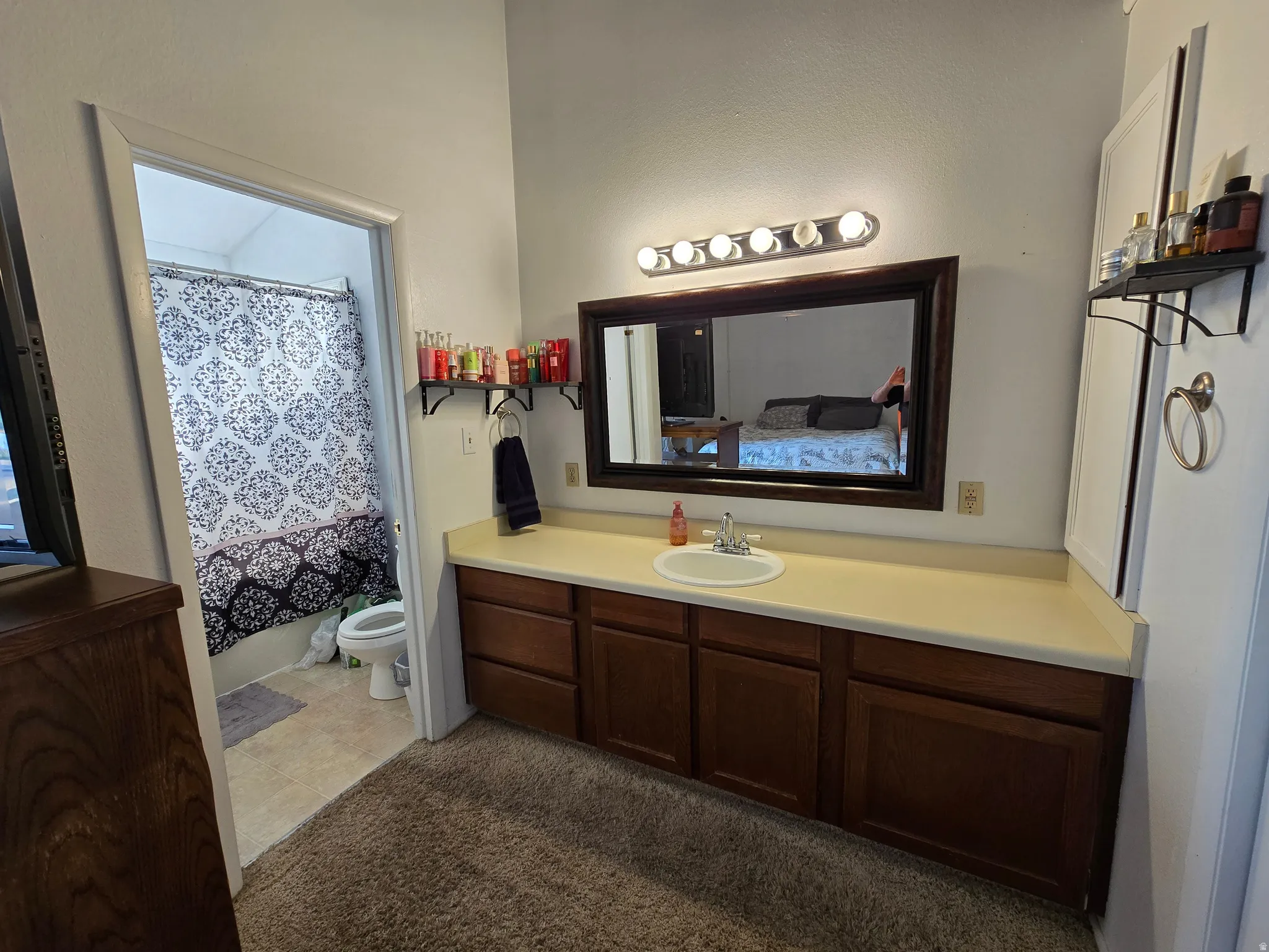 Vanity with integrated sink, wood-finish cabinetry, and overhead lighting