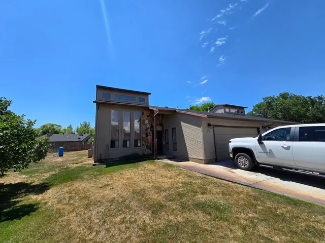 Contemporary architectural styling with stone and siding exterior elements, expansive vertical windows, a two-car garage, and a sloped roofline