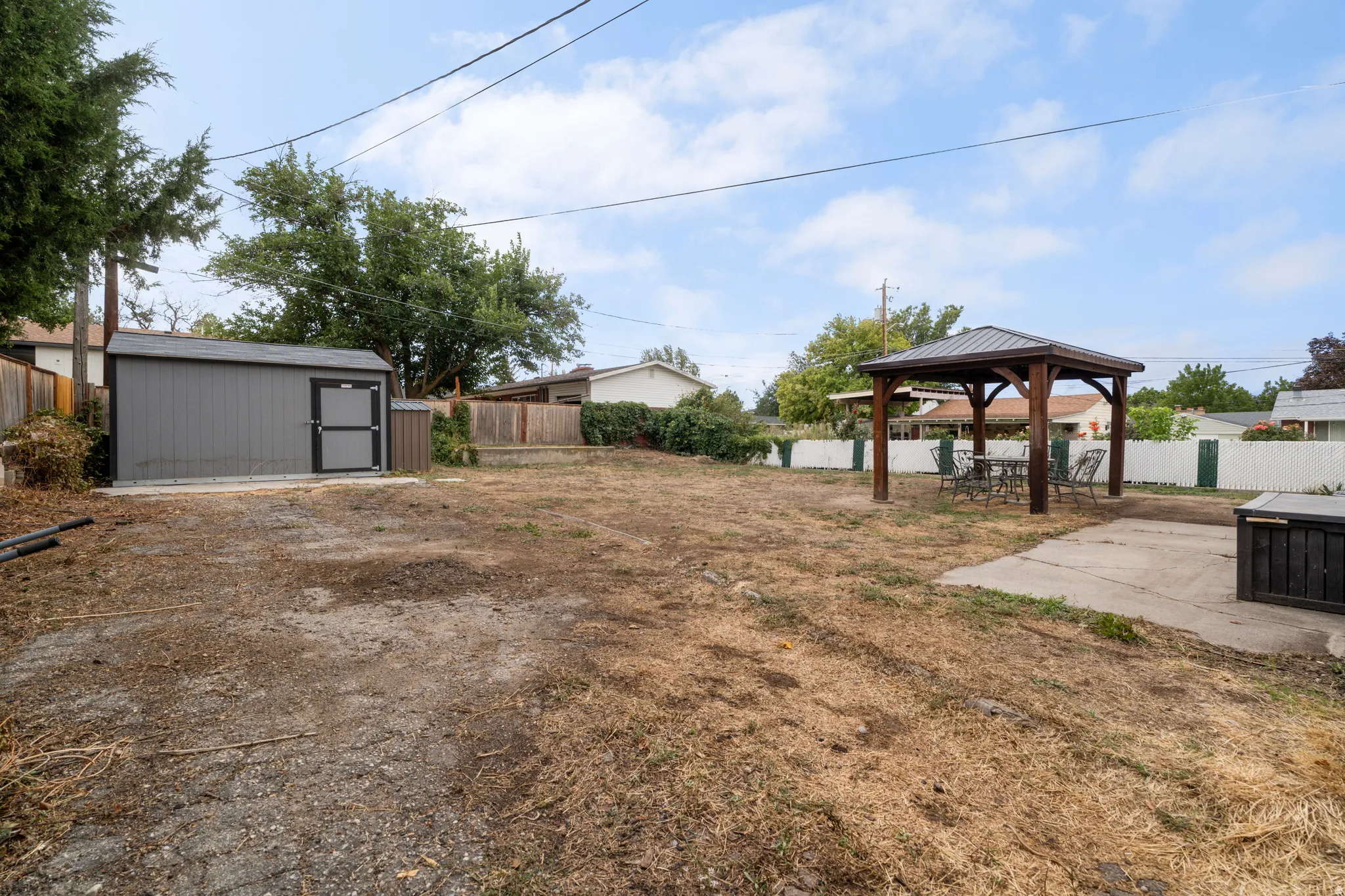Expansive outdoor space featuring a detached storage shed, a wood-frame gazebo with a metal roof, and concrete patio areas