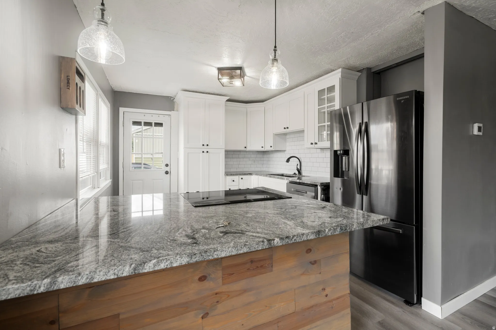 Kitchen featuring a center island with a stone countertop and wood-finish paneling, white shaker-style cabinetry, and stainless steel appliances