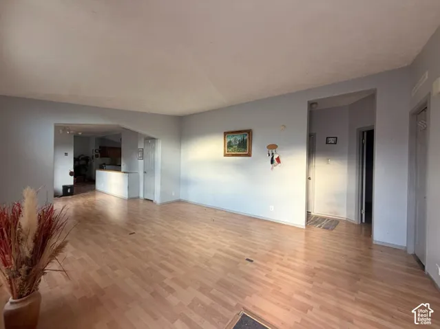Spacious open-concept living area featuring wood-finish flooring throughout, abundant natural light from multiple windows, and clean white walls