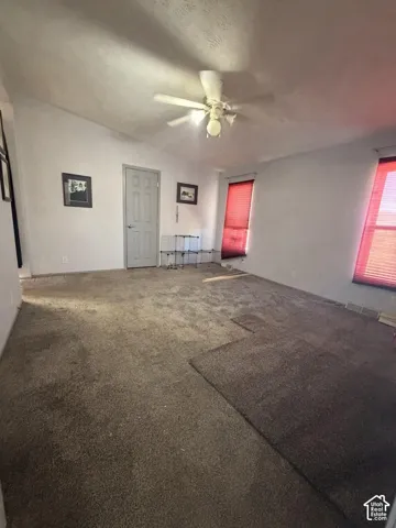 Vaulted ceiling with a ceiling fan light fixture, white walls, and a paneled interior door