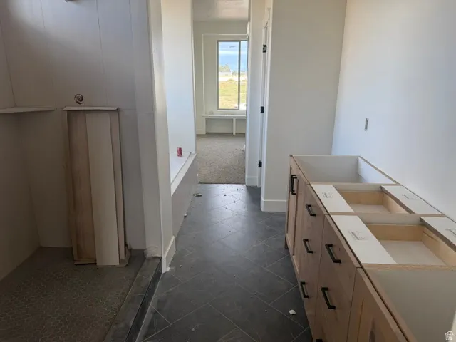 Herringbone-patterned tile flooring, wood-finish vanity with black hardware, and an alcove window