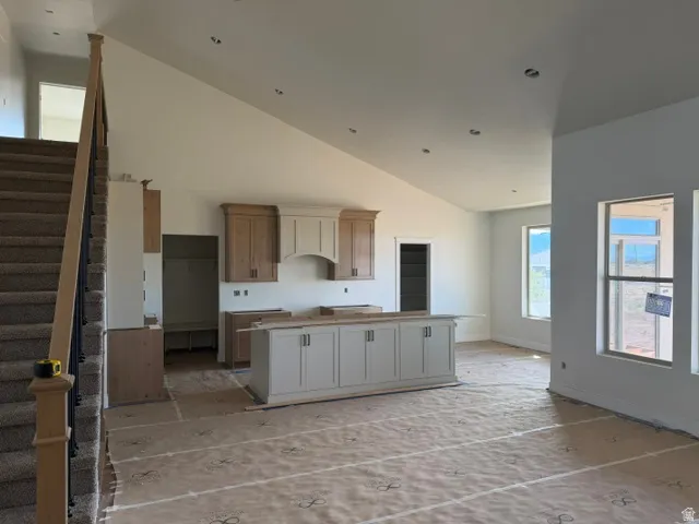 Spacious open-concept living area with vaulted ceilings, recessed lighting, a built-in kitchen island, and large windows