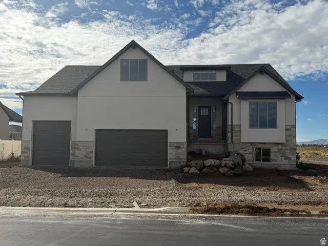 Contemporary exterior featuring a stone and stucco facade, a dark shingle roof, dark-framed windows, and a two-car garage