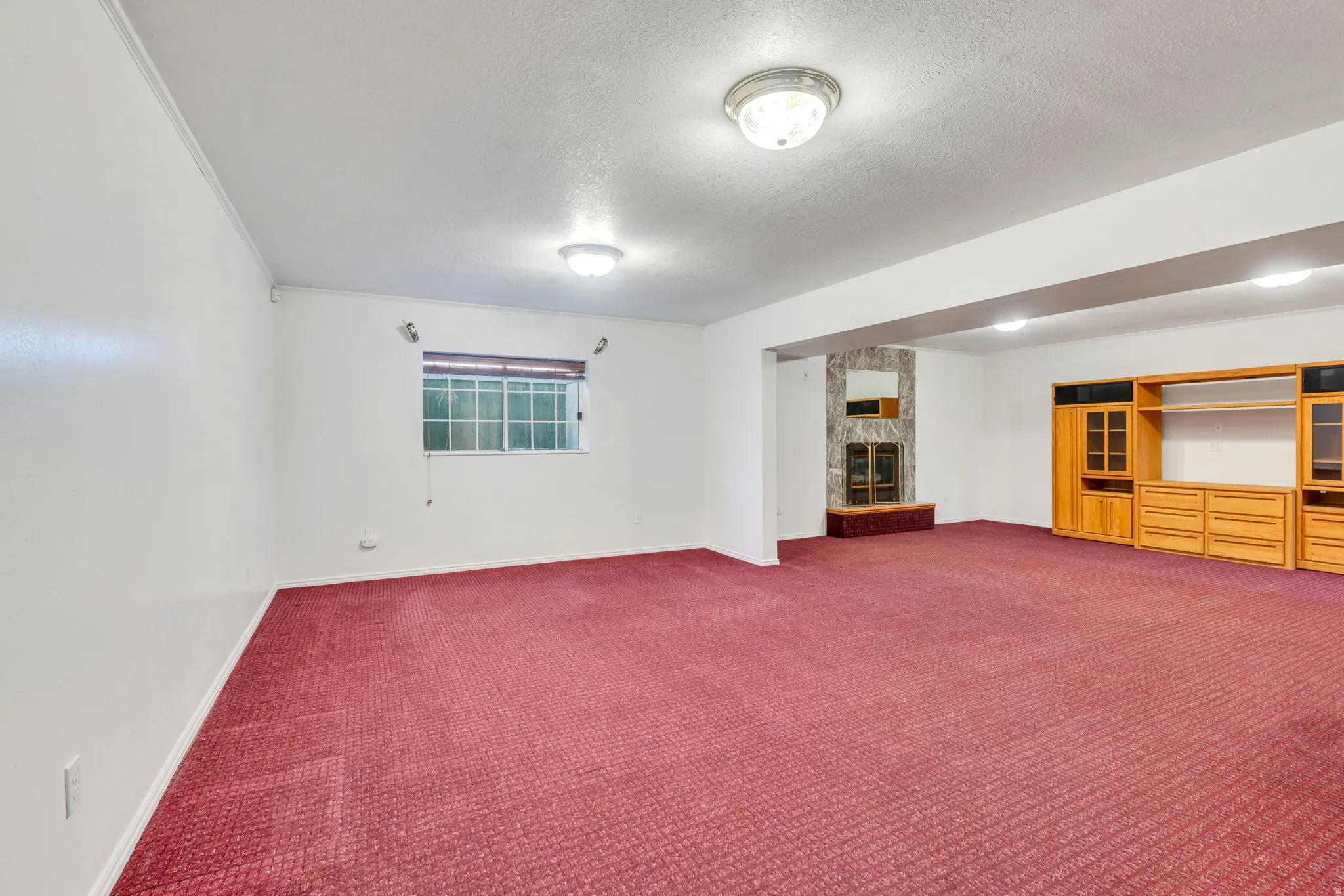 Basement: Spacious great room with recessed lighting, a stone-clad gas fireplace, and a wood-finish shelving unit
