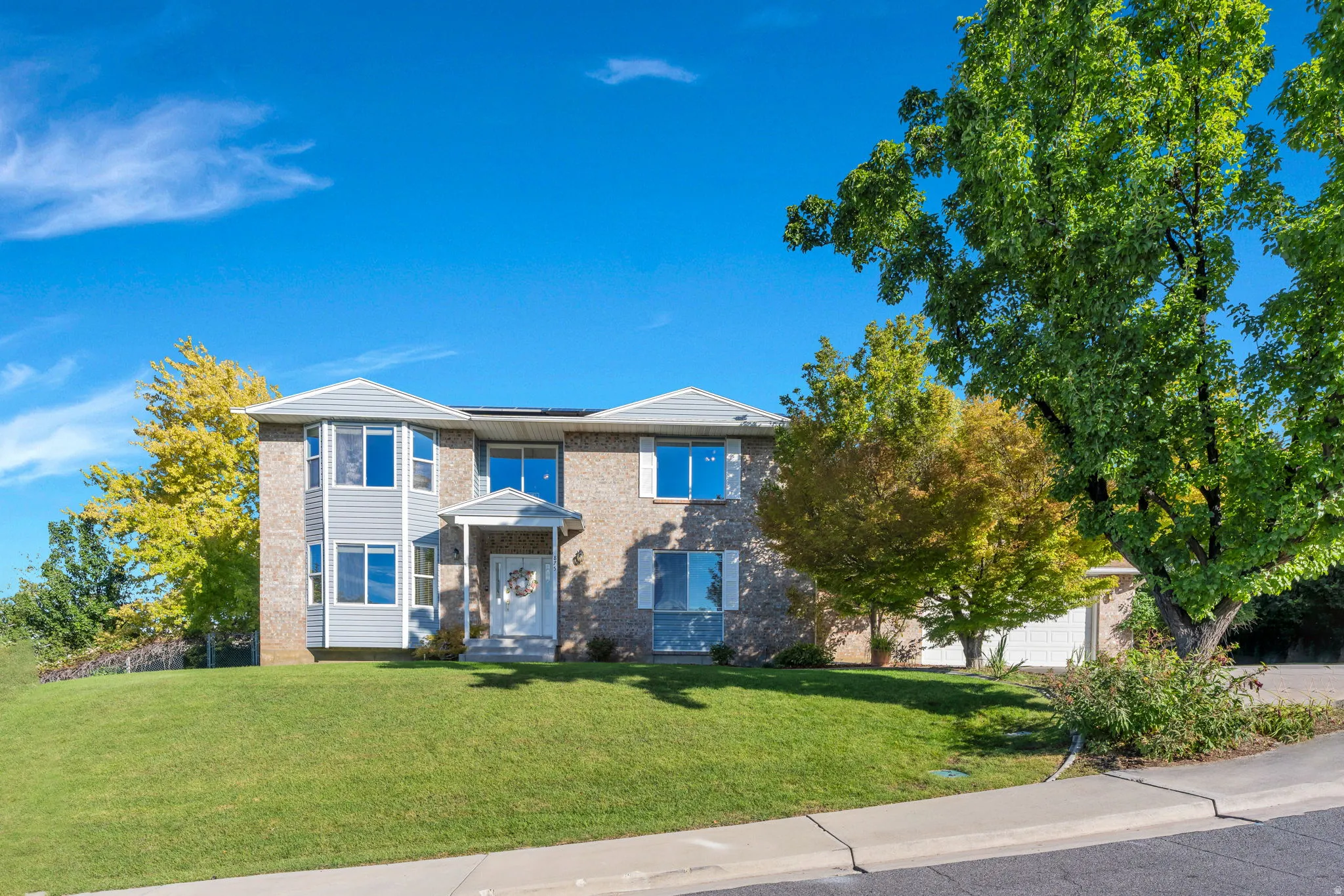Two-story exterior with brick and siding, multiple bay windows, a covered entry, and an integrated garage