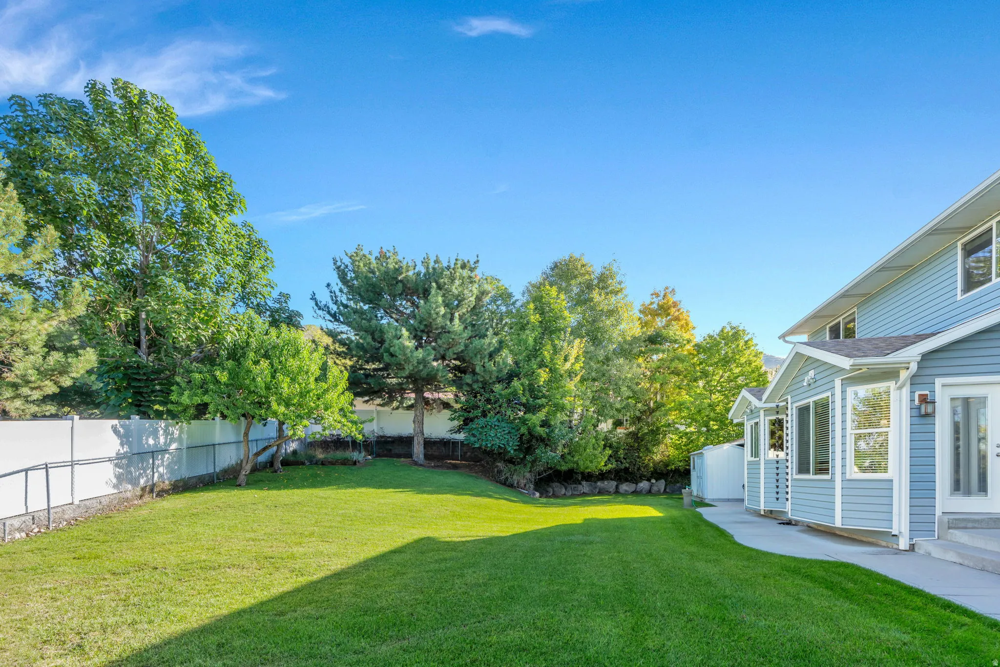 0.35 acre, Expansive/ Secluded grassy yard with mature trees, a privacy fence, and a concrete walkway