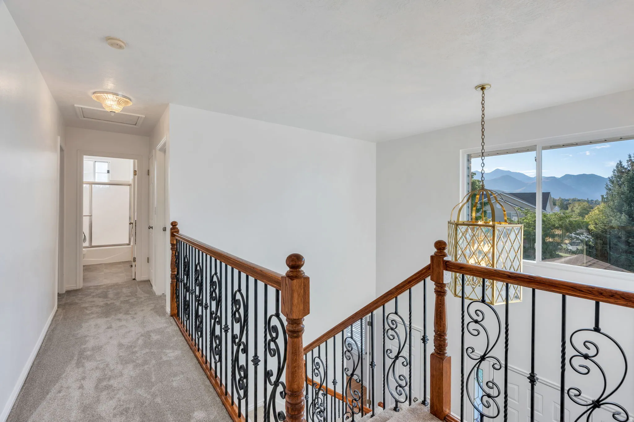 Beautiful open Staircase with wood newel posts, wrought iron balusters, and carpeted treads