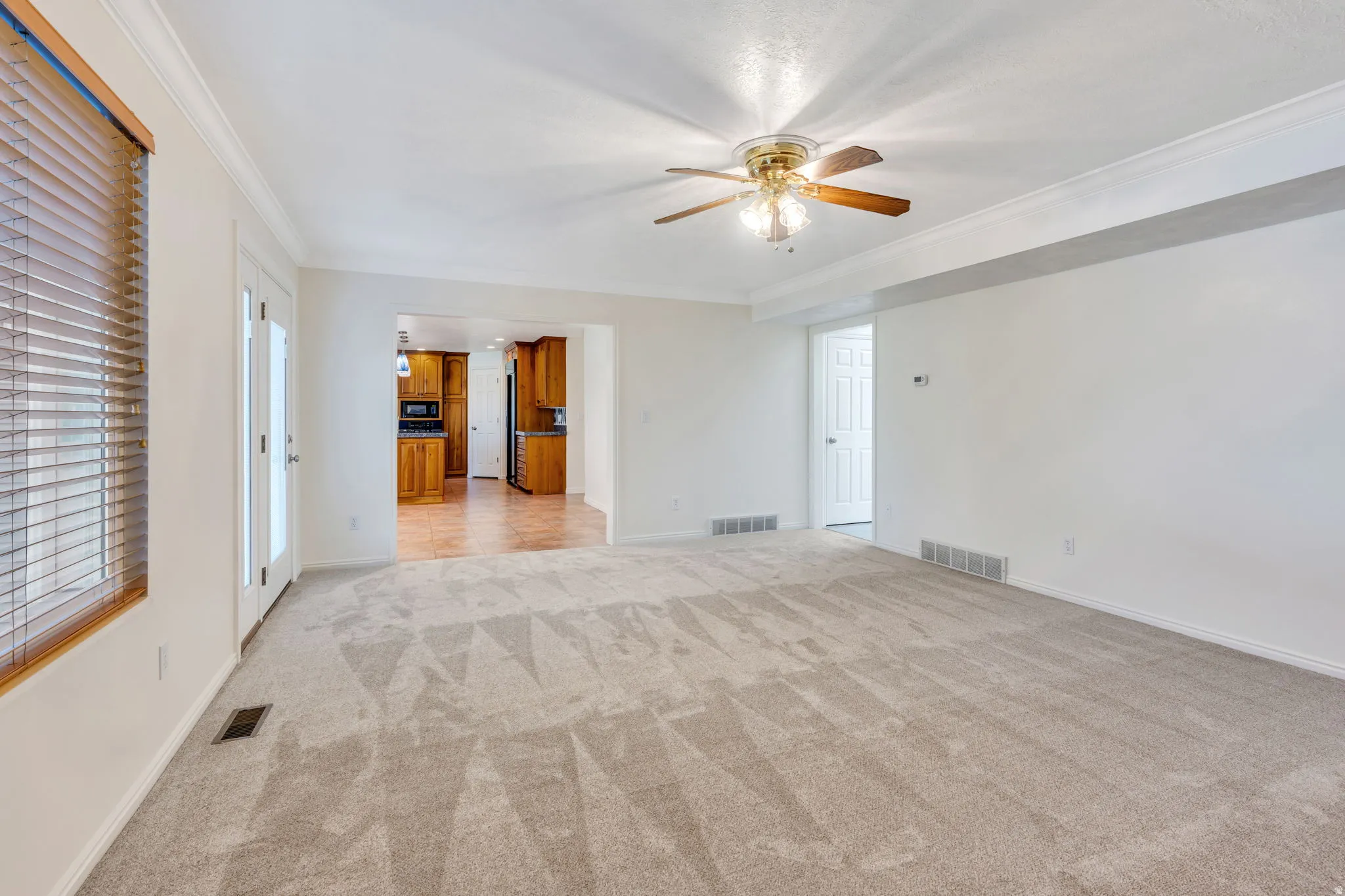 Family Room with new Light-toned wall-to-wall carpeting, white crown molding, and a ceiling fan with integrated lighting