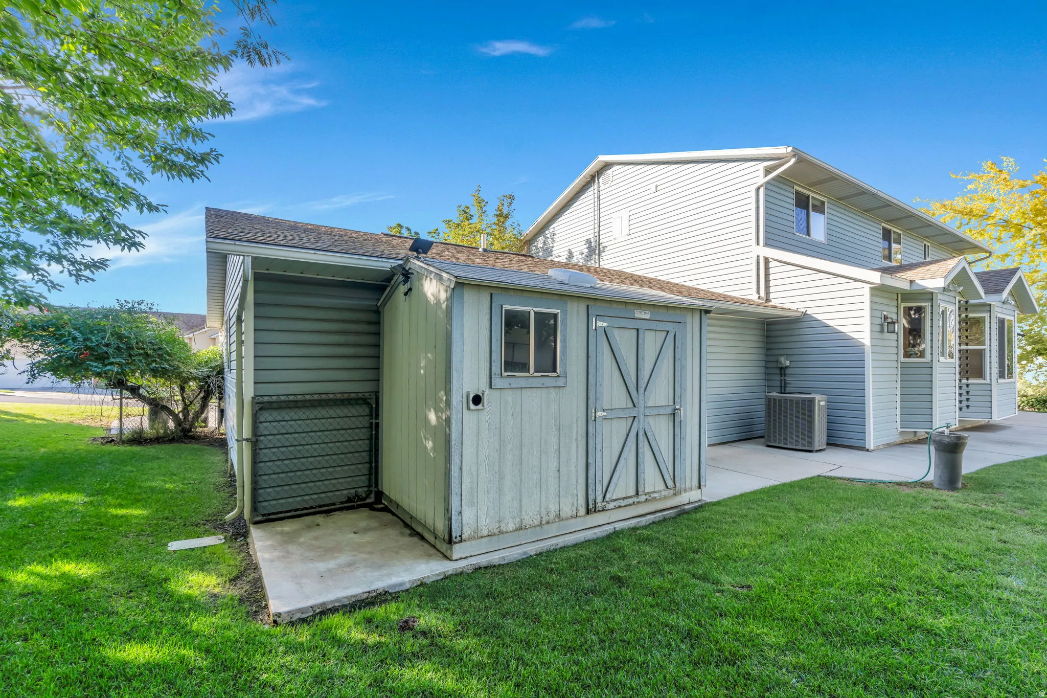 Backyard, Exterior storage shed with a window, concrete pad, and mature landscaping