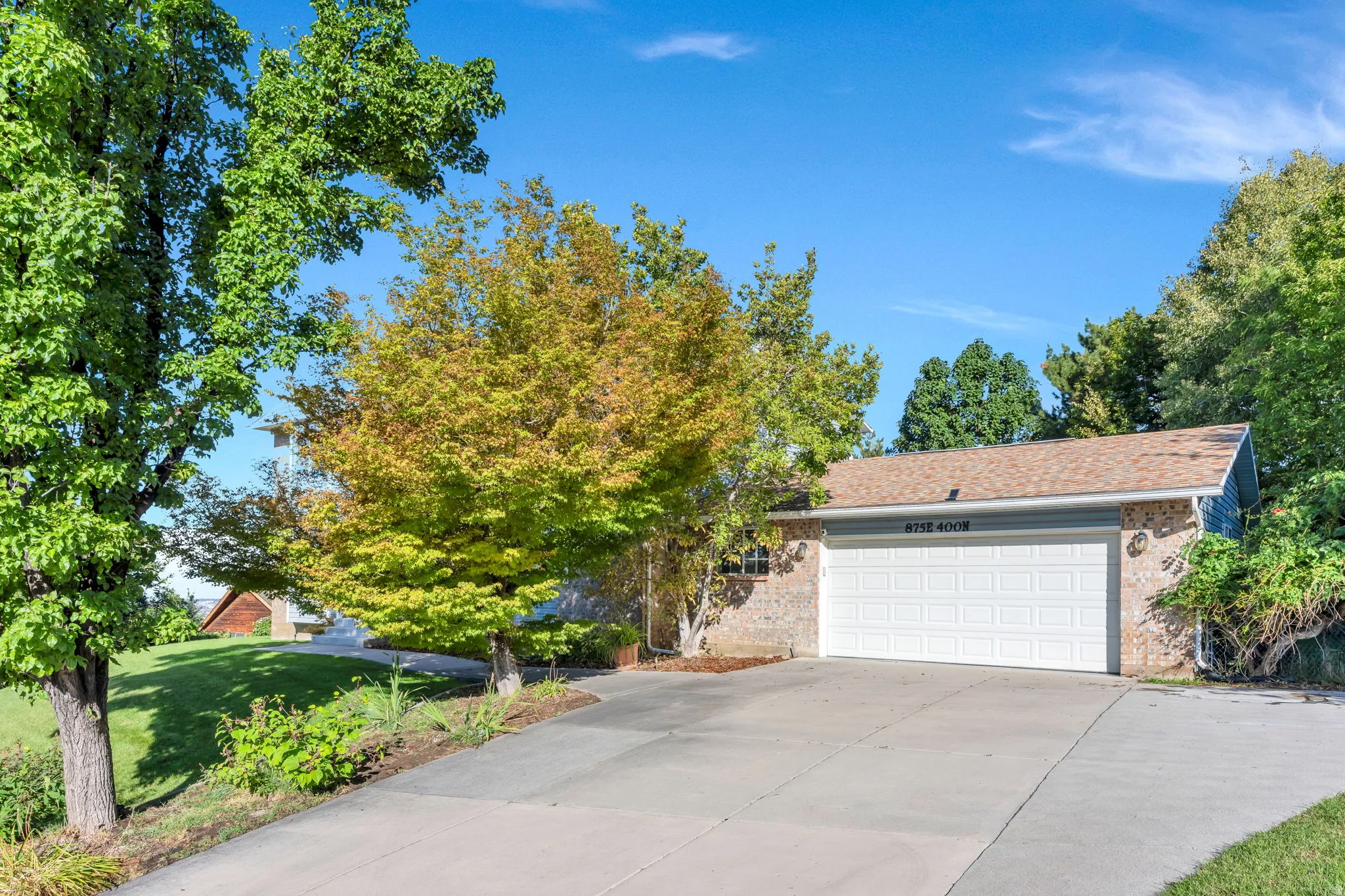 Attached two-car garage with panel door, brick facade, and concrete driveway