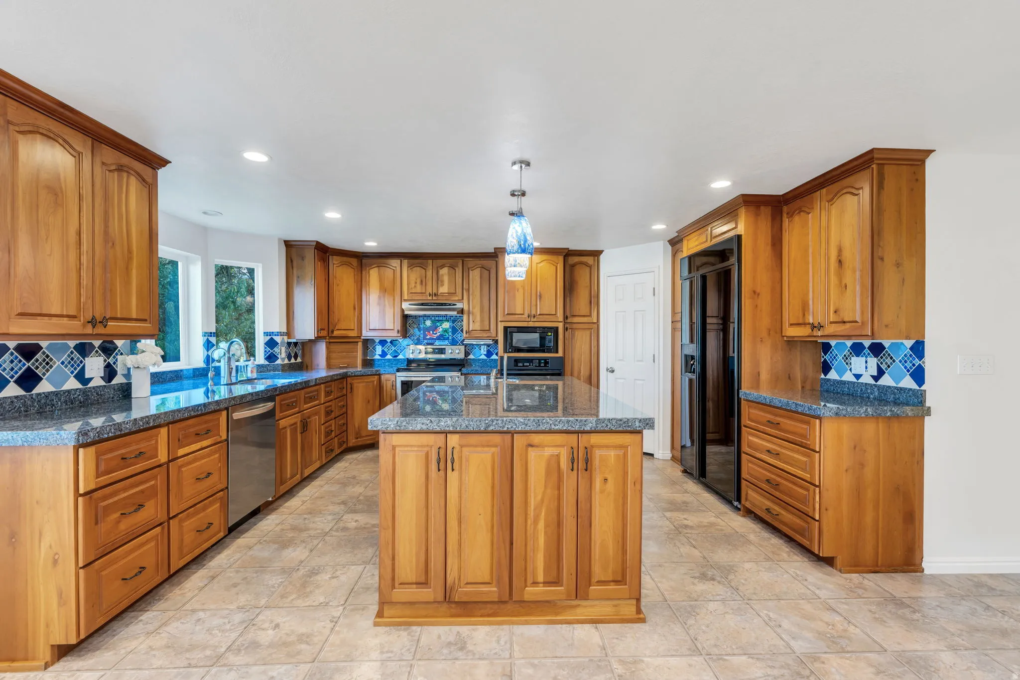 Kitchen featuring wood cabinetry, a central island, granite-style countertops, and stainless steel appliances