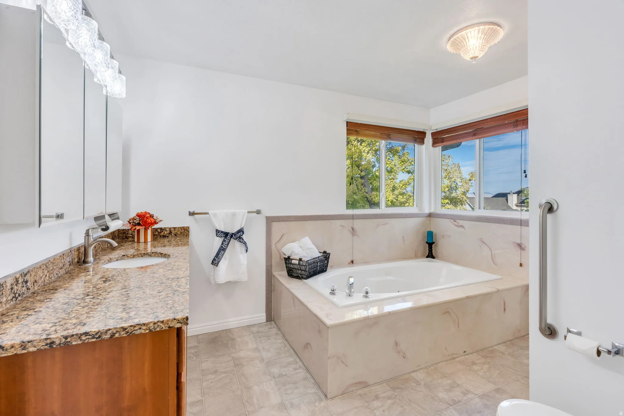 Primary Suite, Jetted soaking tub, corner windows, vanity with granite countertop, and an ornamental ceiling fixture