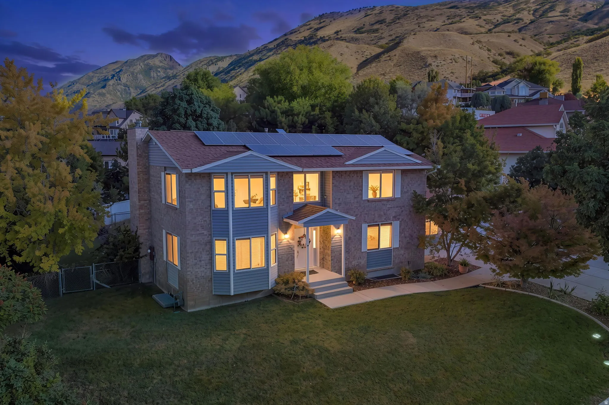 Two-story brick and siding residence featuring a gabled roofline, solar panels, and an inviting front entrance