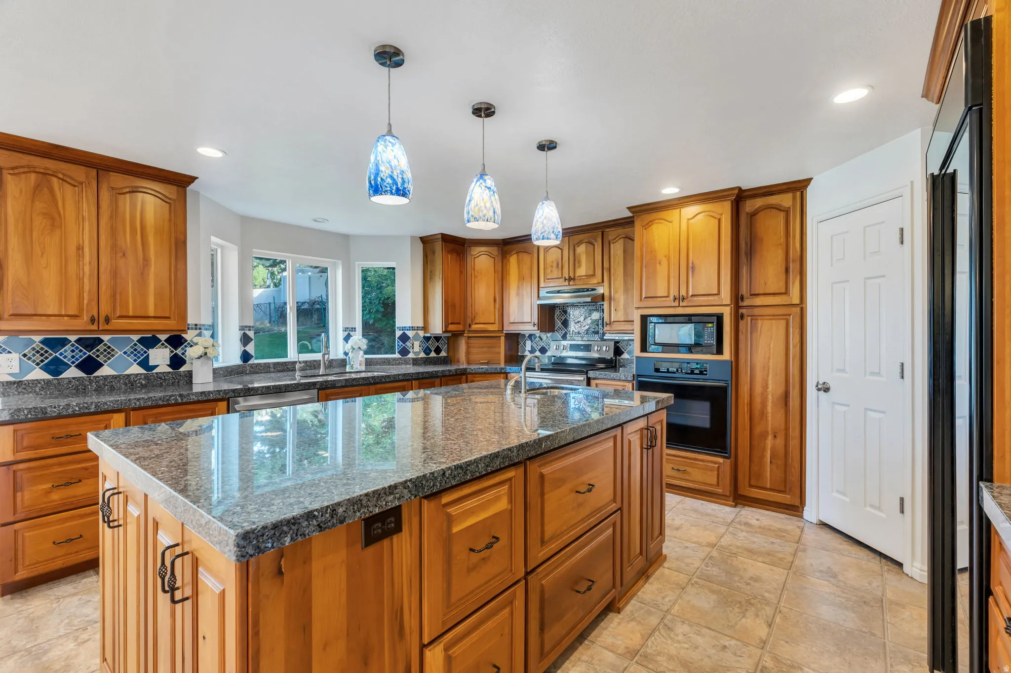 Massive Kitchen featuring wood cabinetry, granite countertops, an integrated oven and microwave, with a large central island.