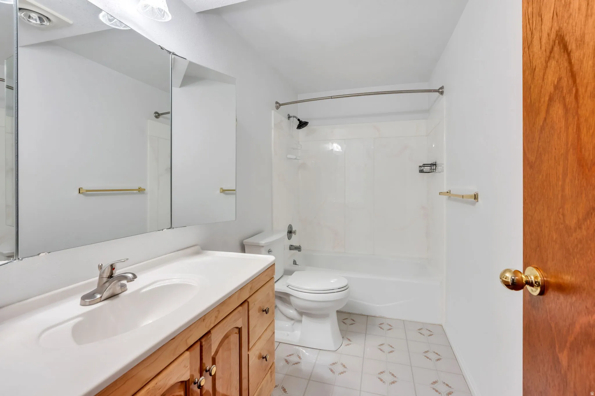 Basement Bathroom featuring a wood-finish vanity with an integrated sink, a mirrored medicine cabinet, and a shower-over-tub combination with white surround.