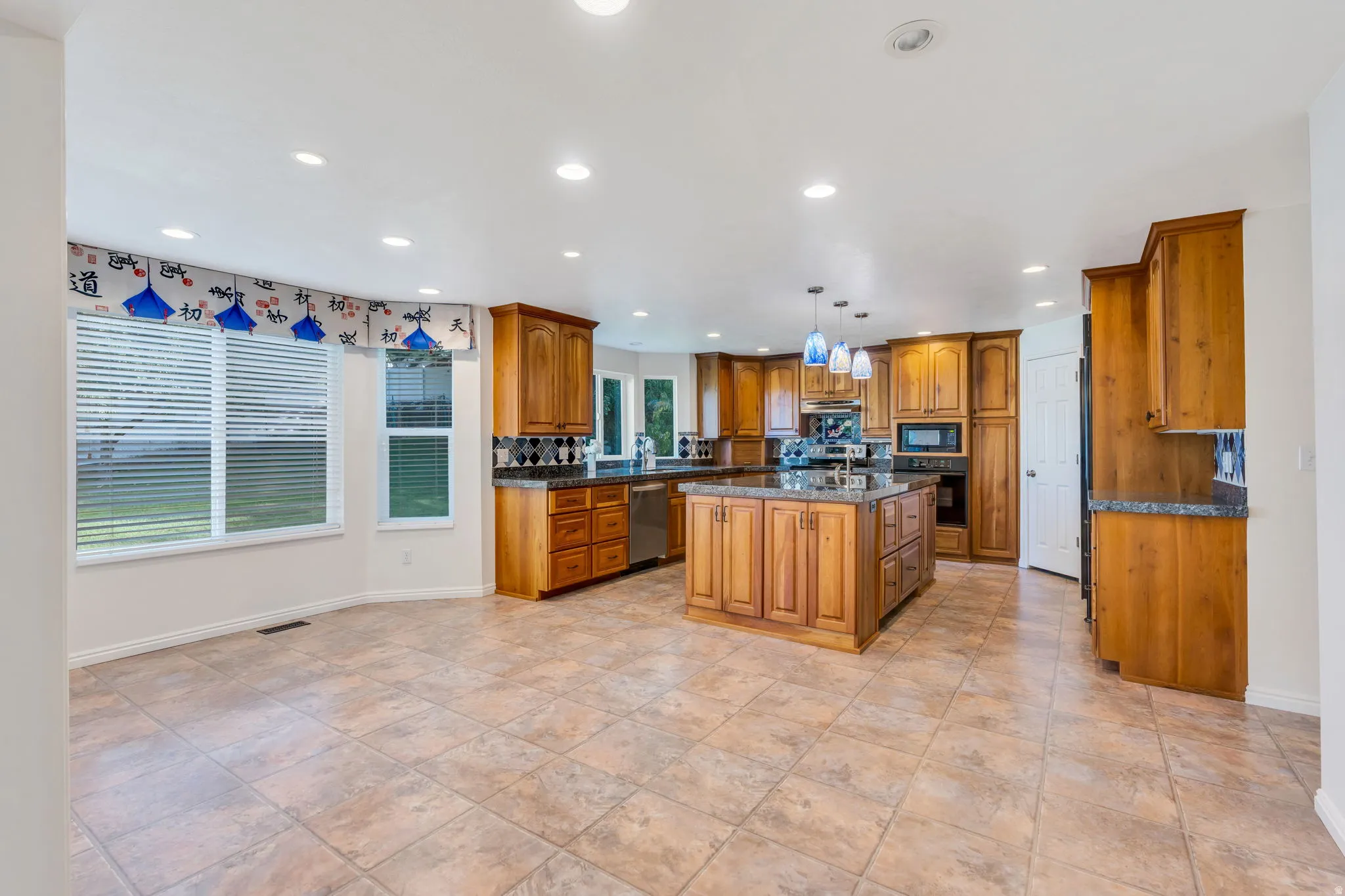 Spacious kitchen featuring a large central island, extensive wood cabinetry, and large area for enormous kitchen table.