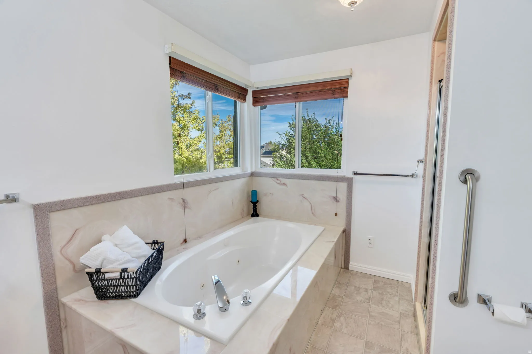 Built-in jetted tub with polished chrome fixtures, surrounded by a light-toned stone finish