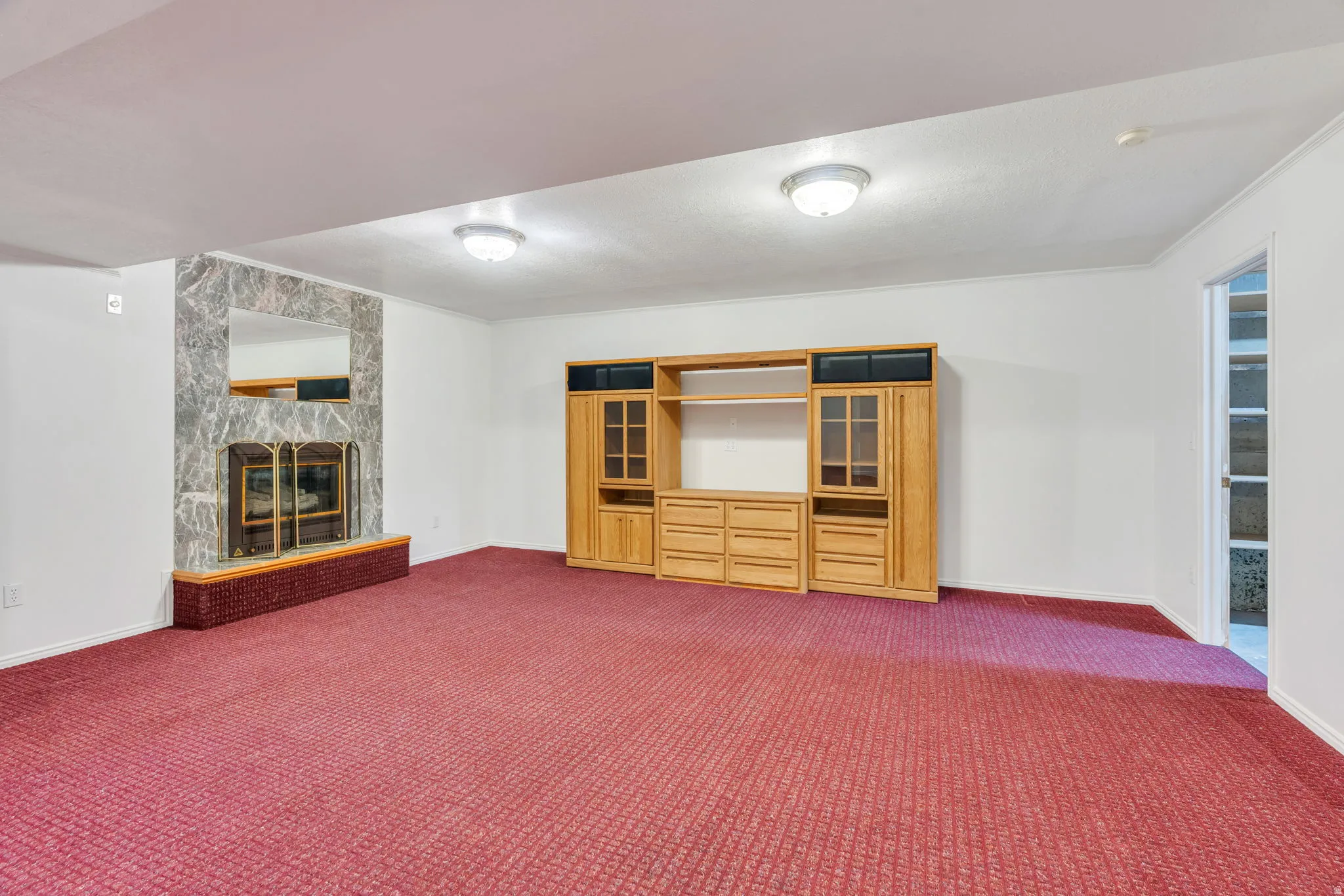 Basement: Spacious great room featuring a stone-surround gas fireplace with a brick hearth and a wood-finish media console