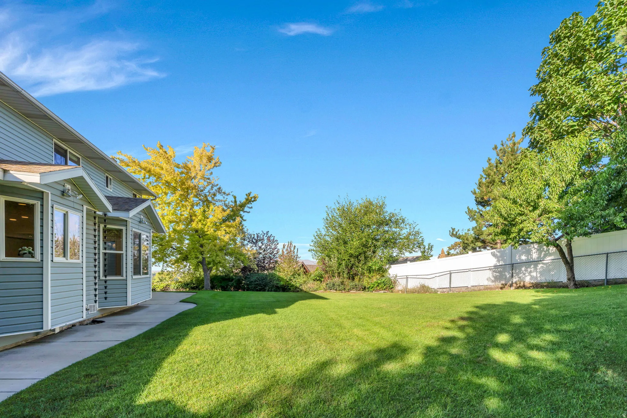 0.35 acre, Expansive/Secluded lawn area, mature trees, concrete pathway, light blue siding, and white window frames