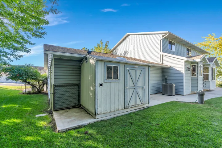 Backyard, Exterior storage shed with a window, concrete pad, and mature landscaping