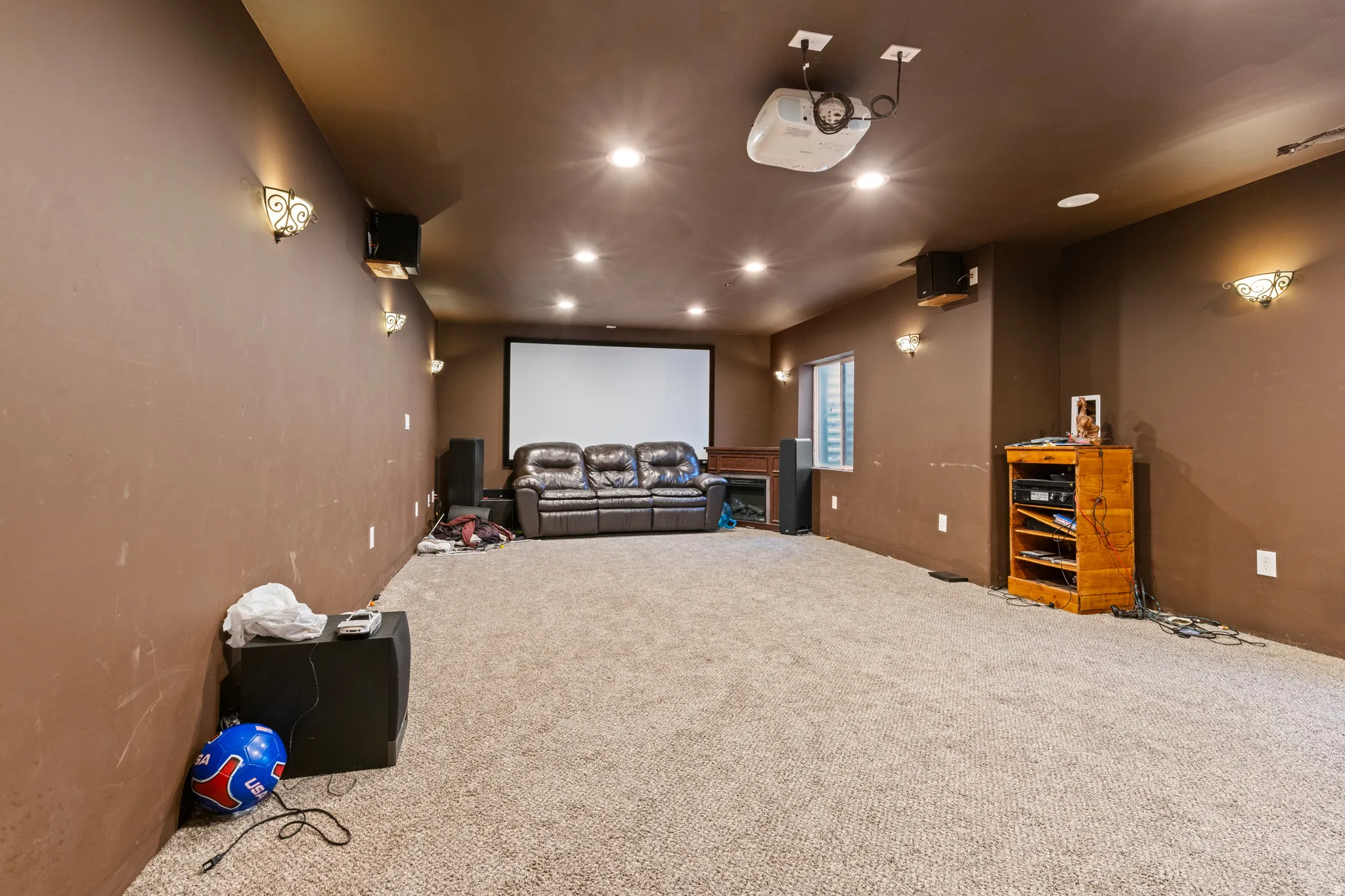 Projector with ceiling mount, recessed lighting, wall-mounted sconces, and a large projection screen