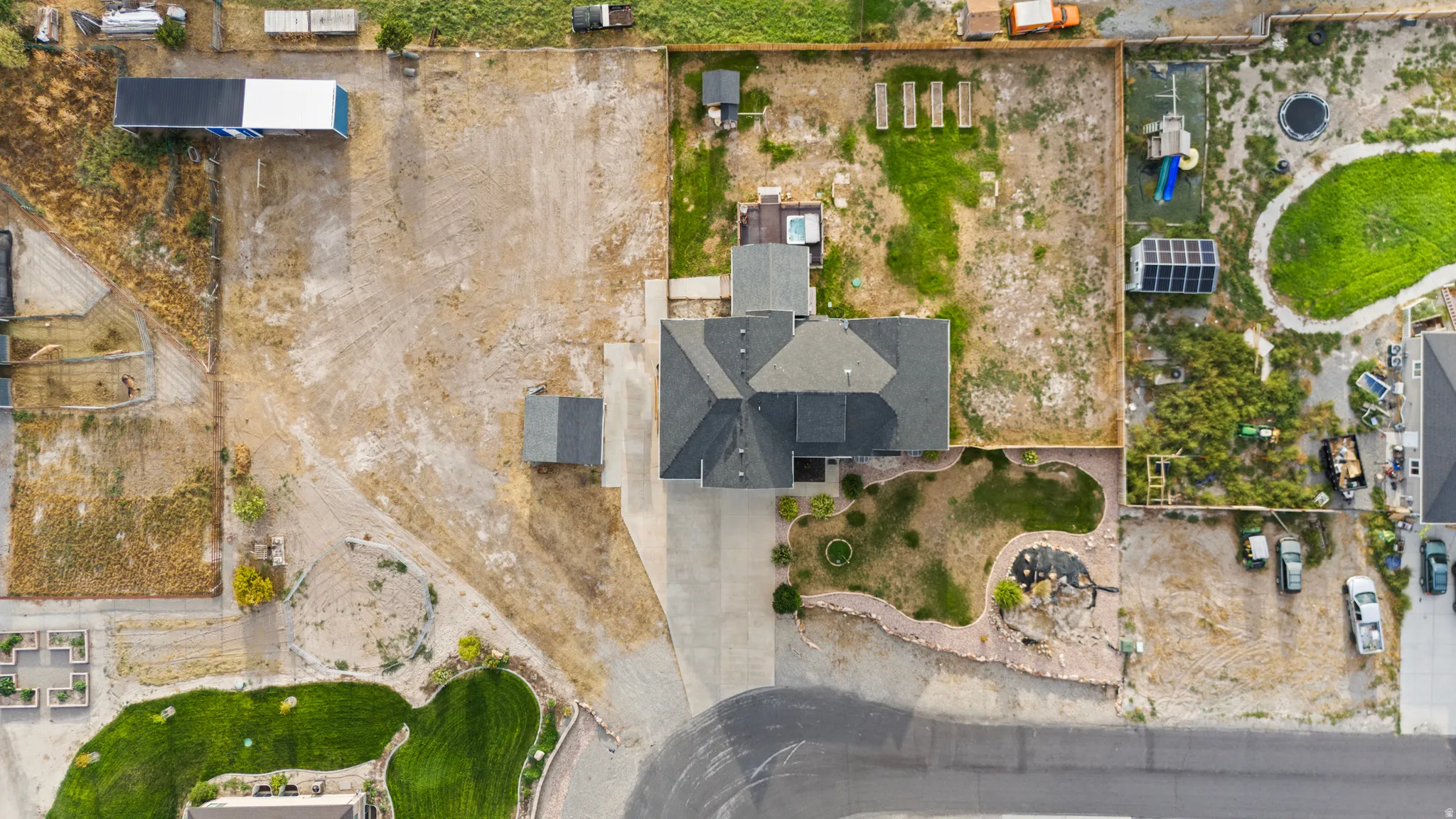Expansive property featuring a large main residence, detached outbuilding, substantial paved driveway, and varied landscaping