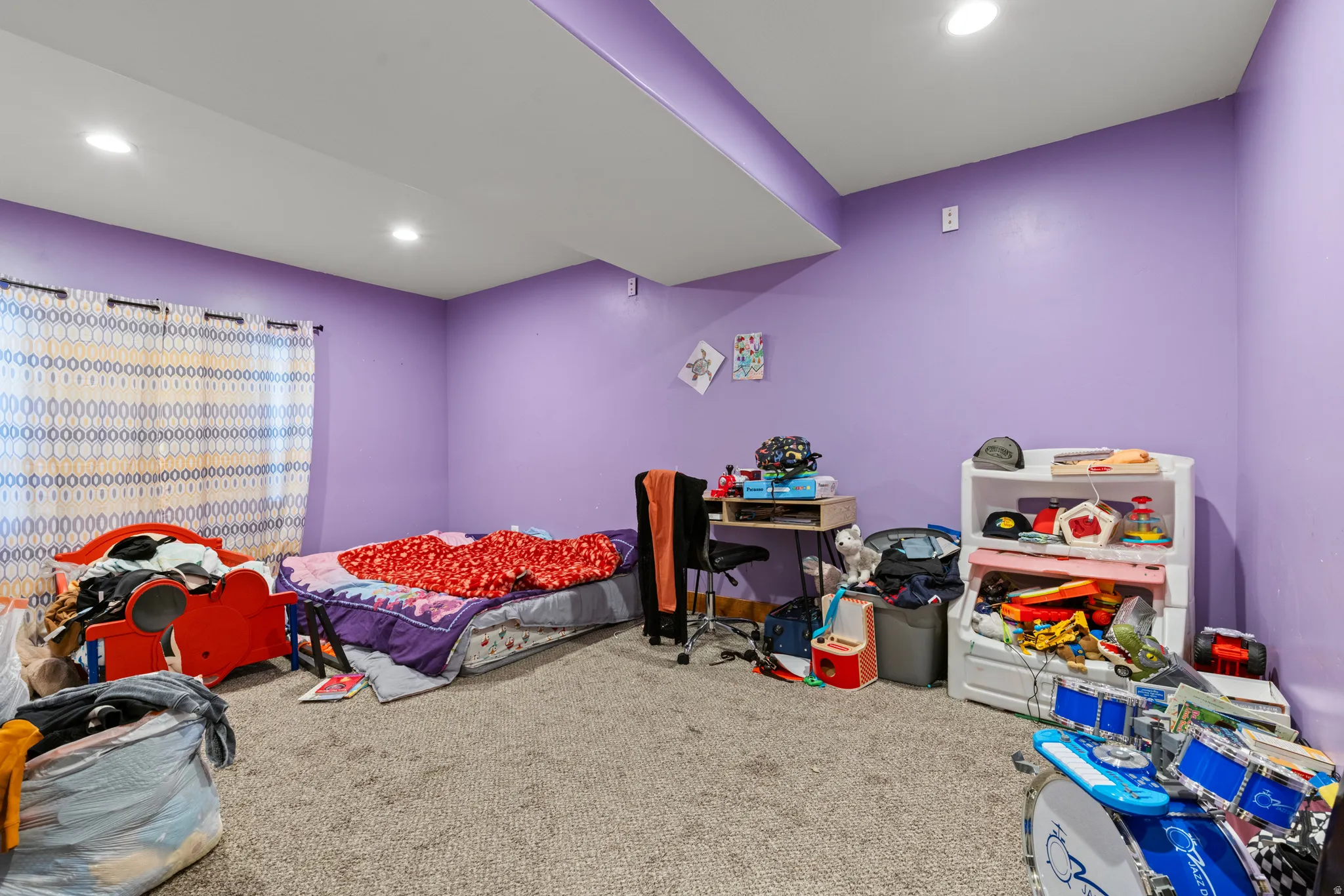 Recessed lighting illuminates the carpeted flooring and purple walls