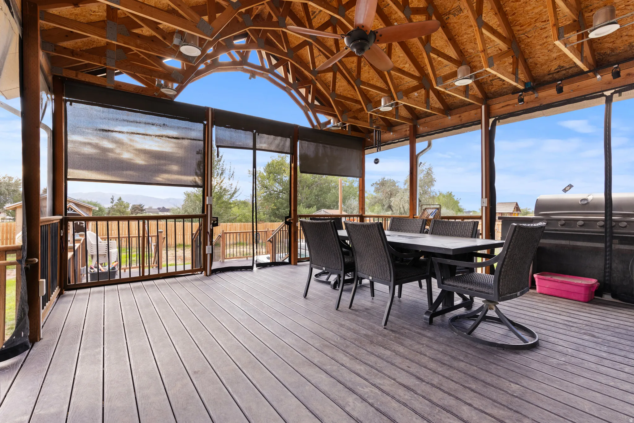 Covered outdoor living space featuring a wood-finish vaulted ceiling, exposed beams, and a ceiling fan