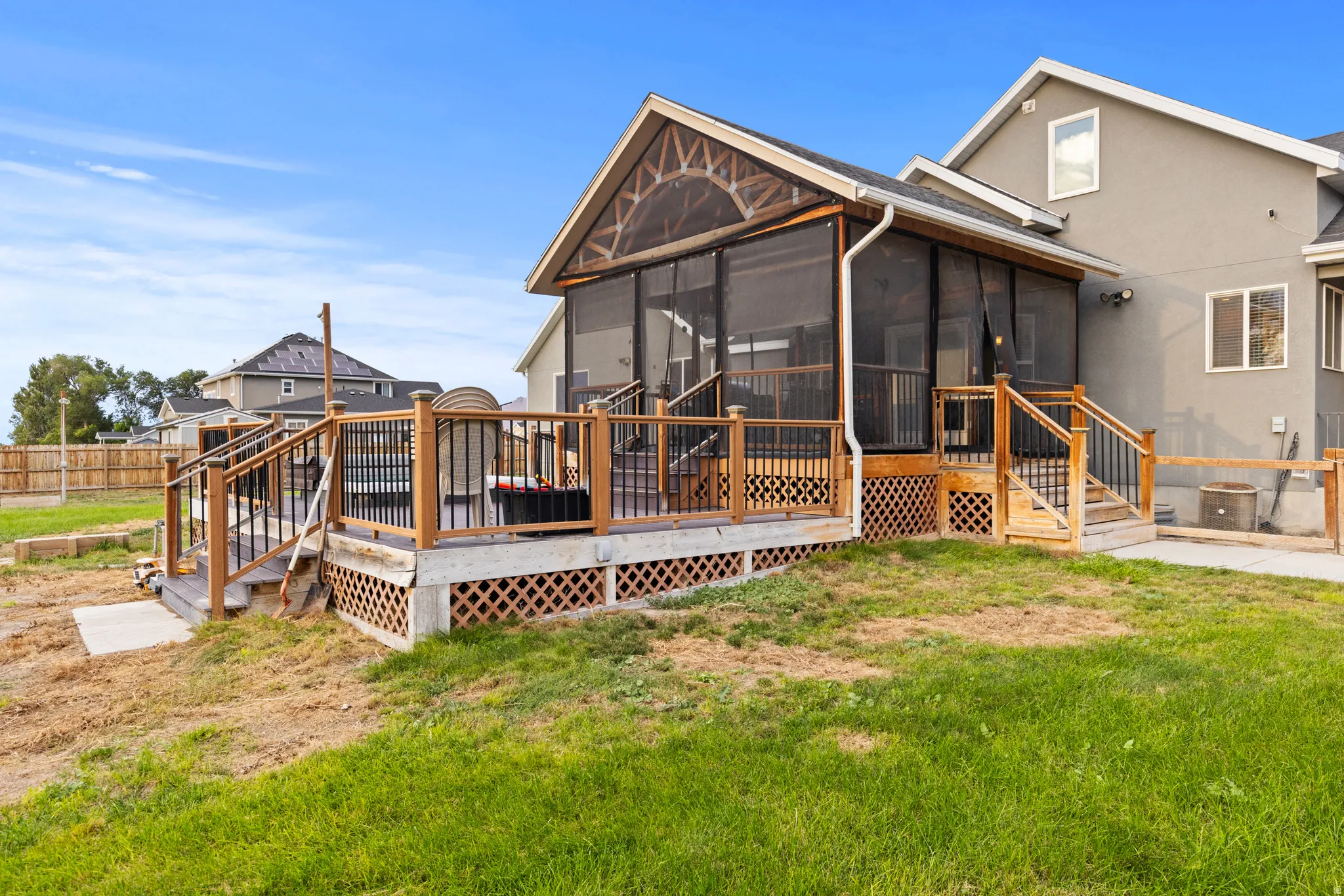 Screened porch with vaulted ceiling, wood deck with black metal balusters, and a stucco exterior