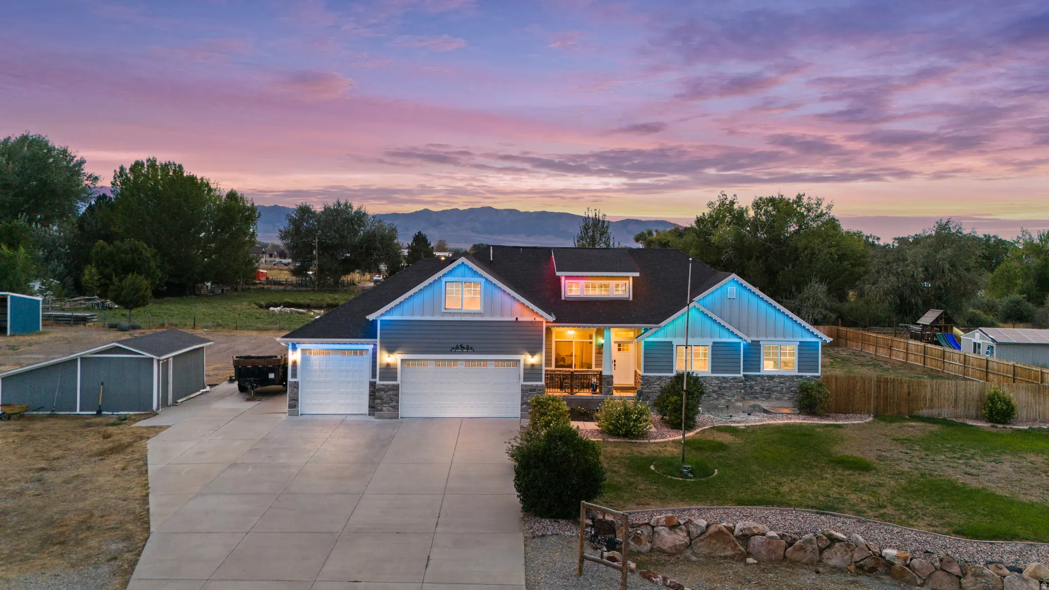 Contemporary residence featuring a two-car garage, stone accents, and a paved driveway