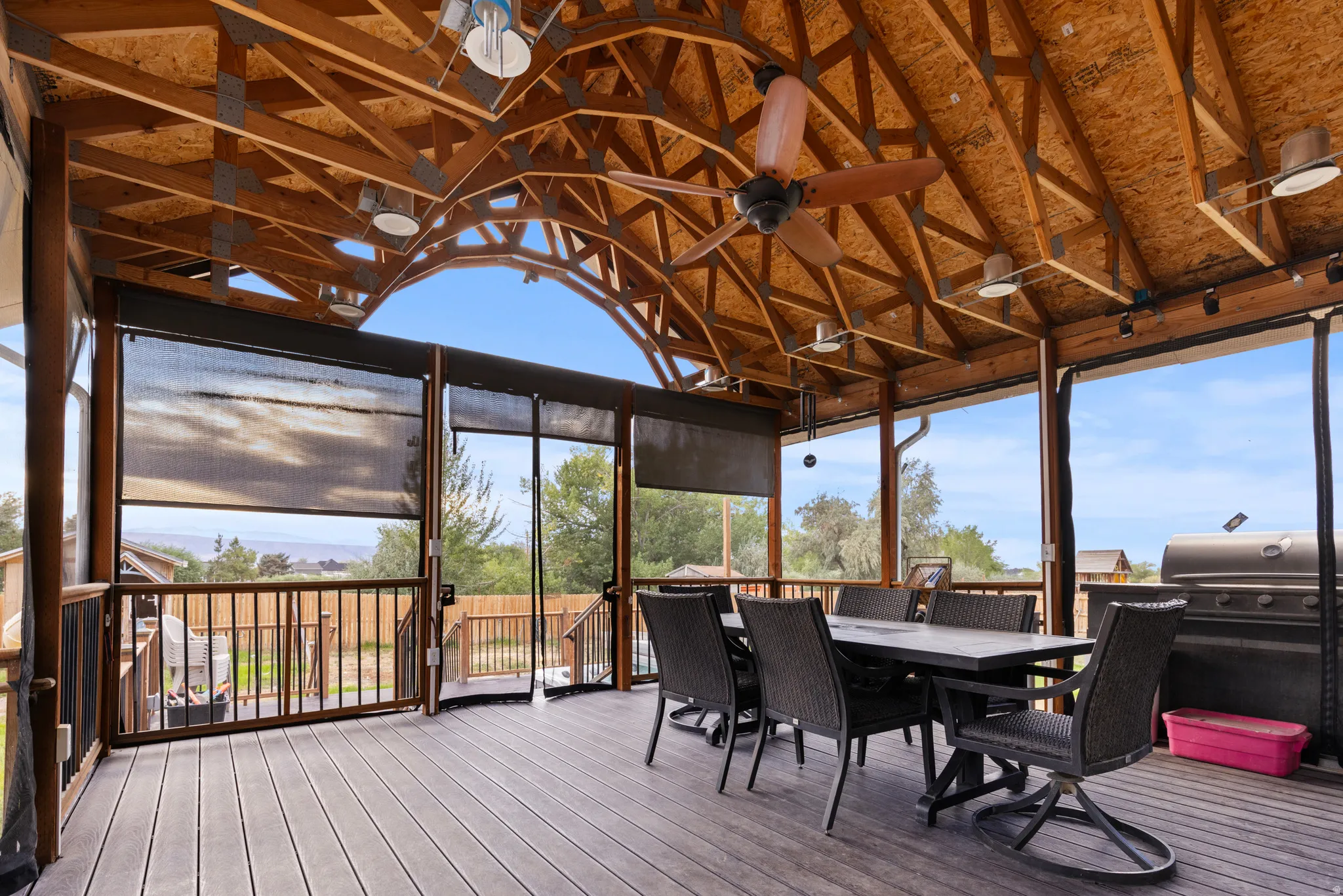 Expansive covered deck featuring exposed wood beam ceiling, multiple ceiling fans, recessed lighting, and roller shades