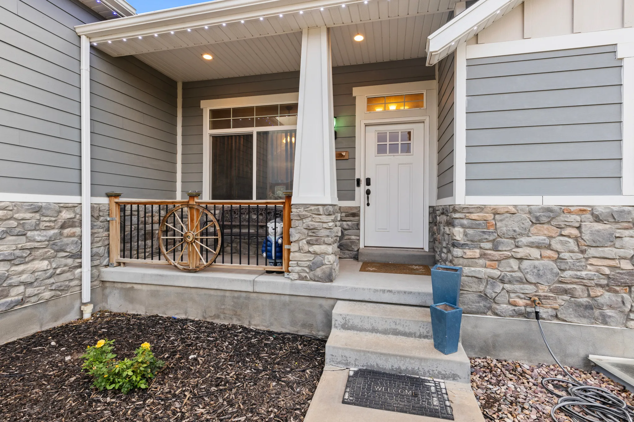 Front exterior featuring stone wainscoting, horizontal siding, and a covered porch