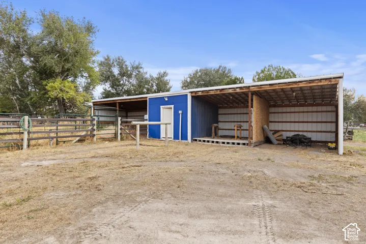 Metal-sided outbuilding with an attached lean-to structure, wood-framed overhang, and perimeter fencing.  2 horse corrals and 2 loafing sheds.  Hay storage.