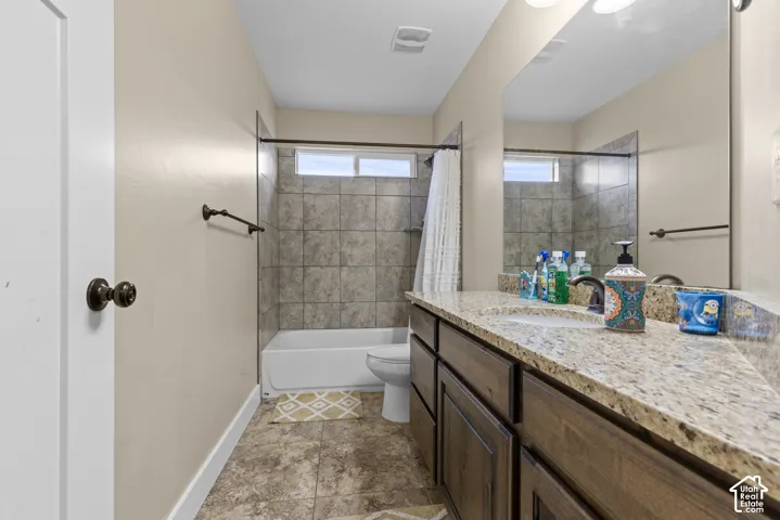 Bathroom featuring a sink with a granite-style countertop, a built-in tub with tile surround, and a rectangular window