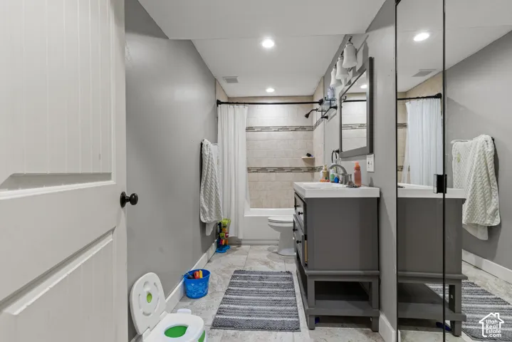 Full-length mirror closet, recessed ceiling lighting, light gray wall paint, tiled shower/bathtub, and a vanity with an integrated sink