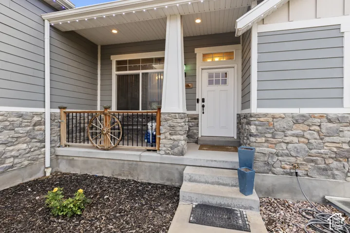 Front exterior featuring stone wainscoting, horizontal siding, and a covered porch