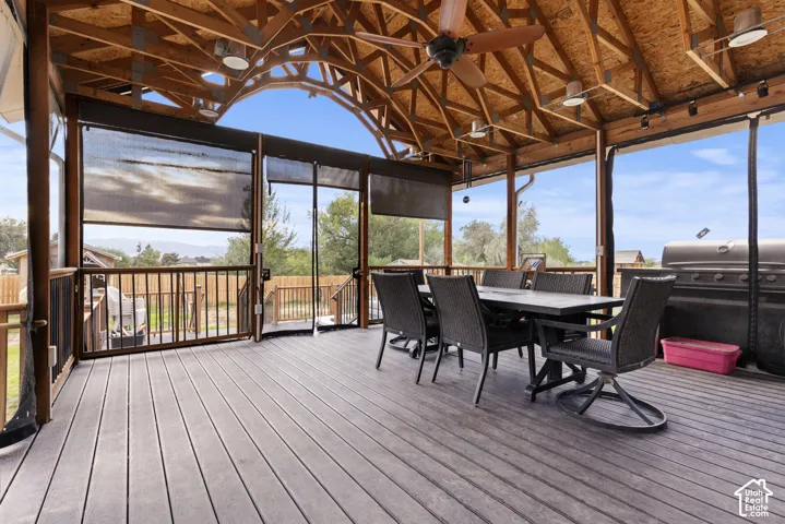 Covered outdoor living space featuring a wood-finish vaulted ceiling, exposed beams, and a ceiling fan