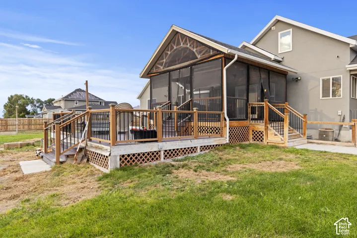 Screened porch with vaulted ceiling, wood deck with black metal balusters, and a stucco exterior
