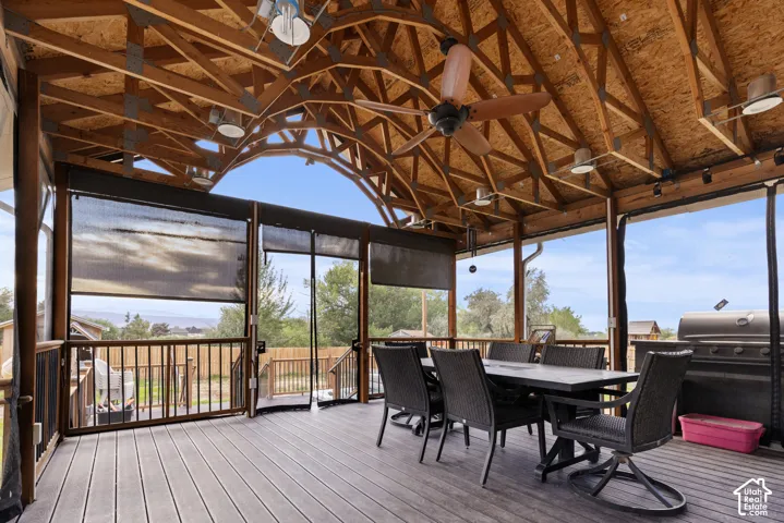 Expansive covered deck featuring exposed wood beam ceiling, multiple ceiling fans, recessed lighting, and roller shades