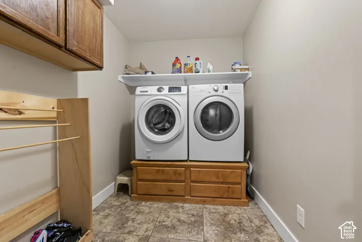 Laundry area featuring wood-finish cabinetry, a built-in wood-finish drying rack, a white wall shelf, and tiled flooring