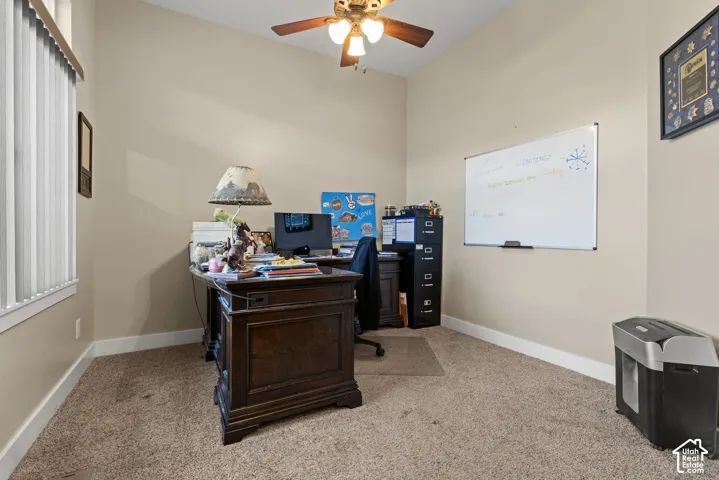 Neutral tone wall paint, vaulted ceiling, ceiling fan with light fixture, vertical window blinds, and carpet flooring