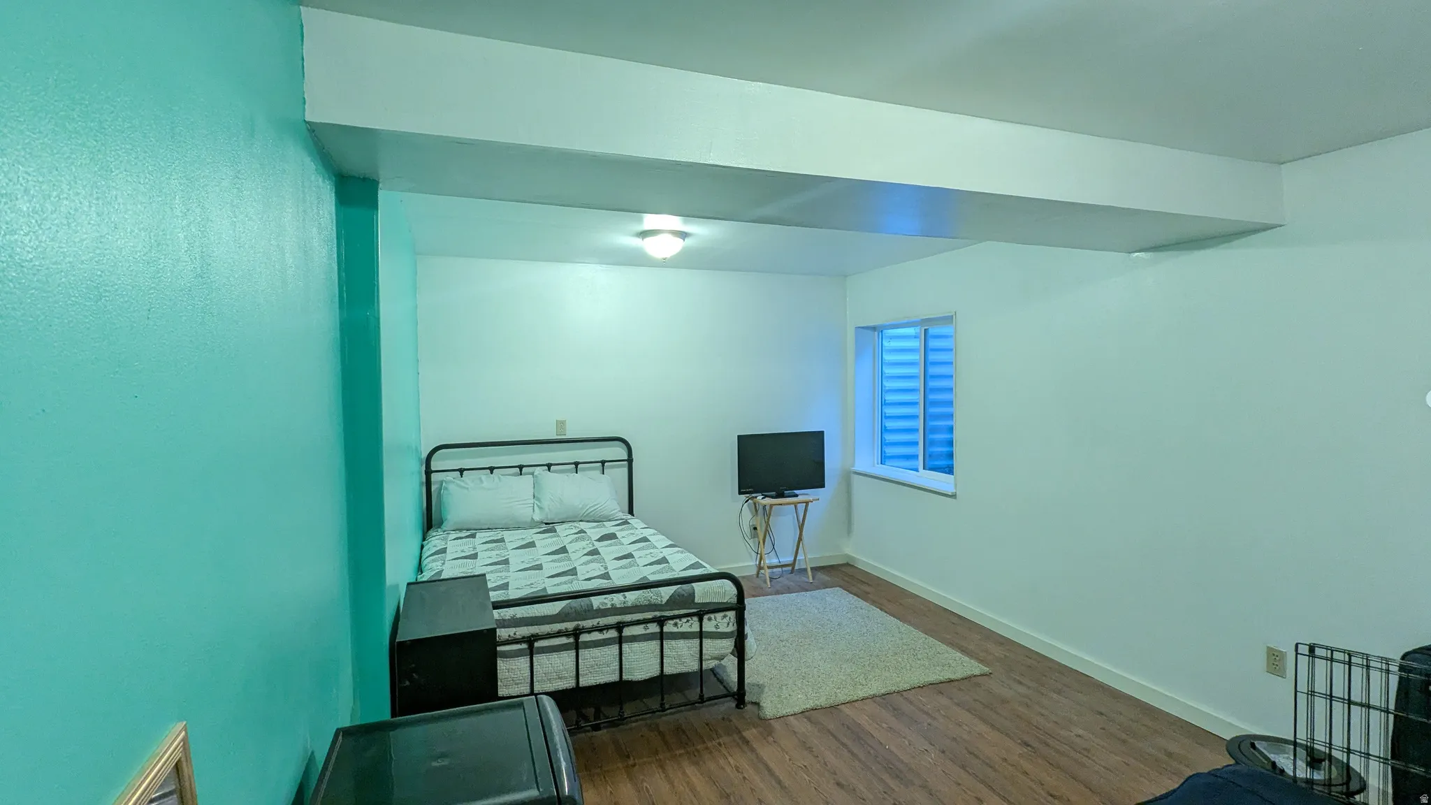Recessed window with horizontal blinds, wood-finish flooring, and overhead flush-mount lighting