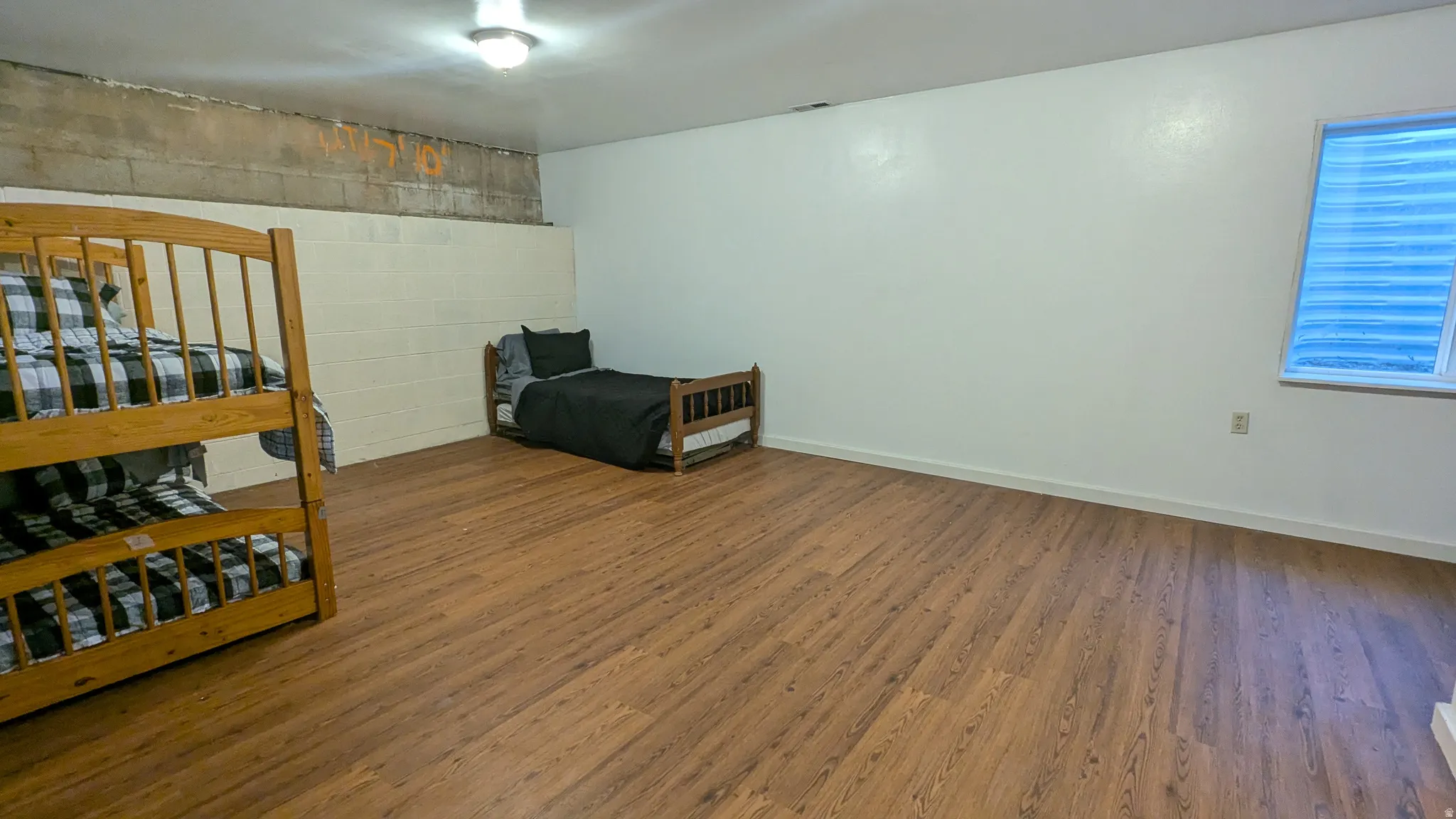 Wood-finish flooring with white painted walls and a window featuring horizontal blinds