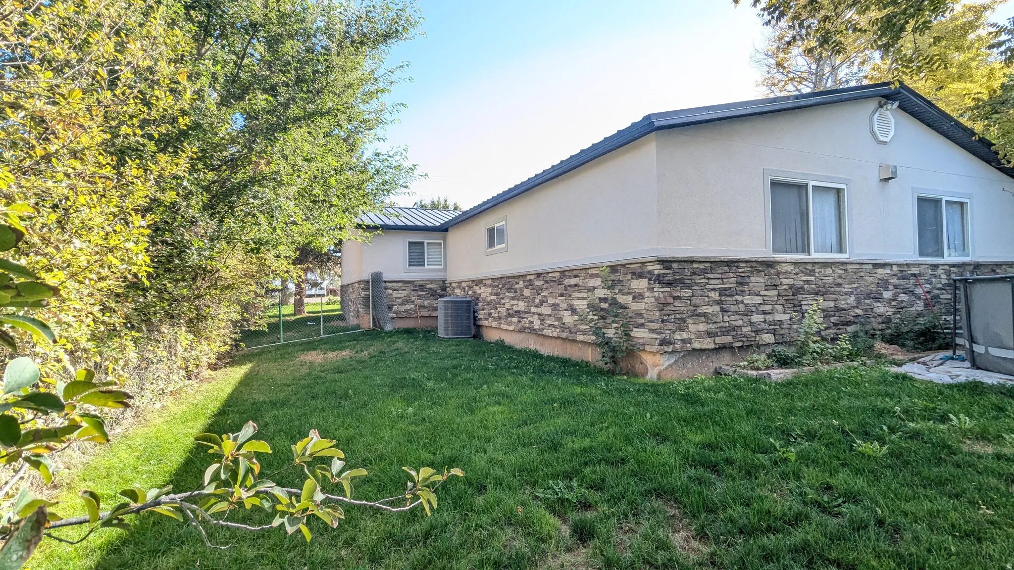 Stucco exterior with a stone veneer foundation, multiple sliding windows, and a manicured lawn