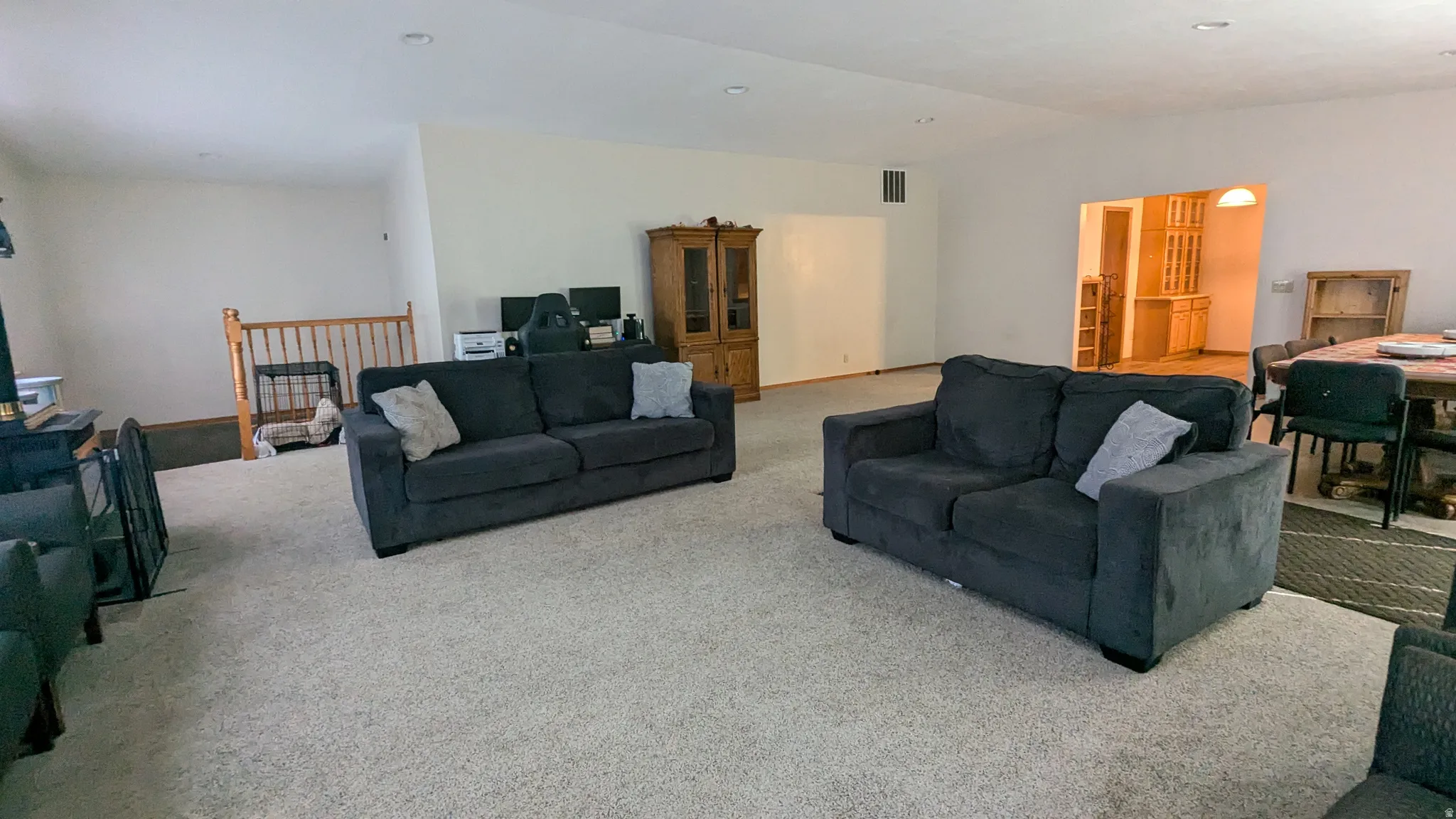 Spacious room with light-toned walls, recessed lighting, and a large carpeted area
