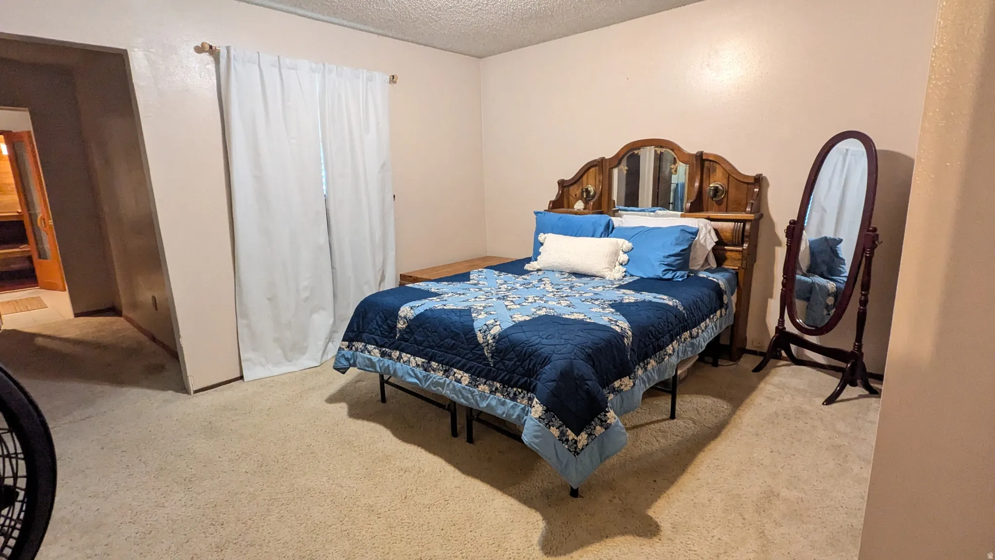 Wall-to-wall carpeting and a window with white curtains