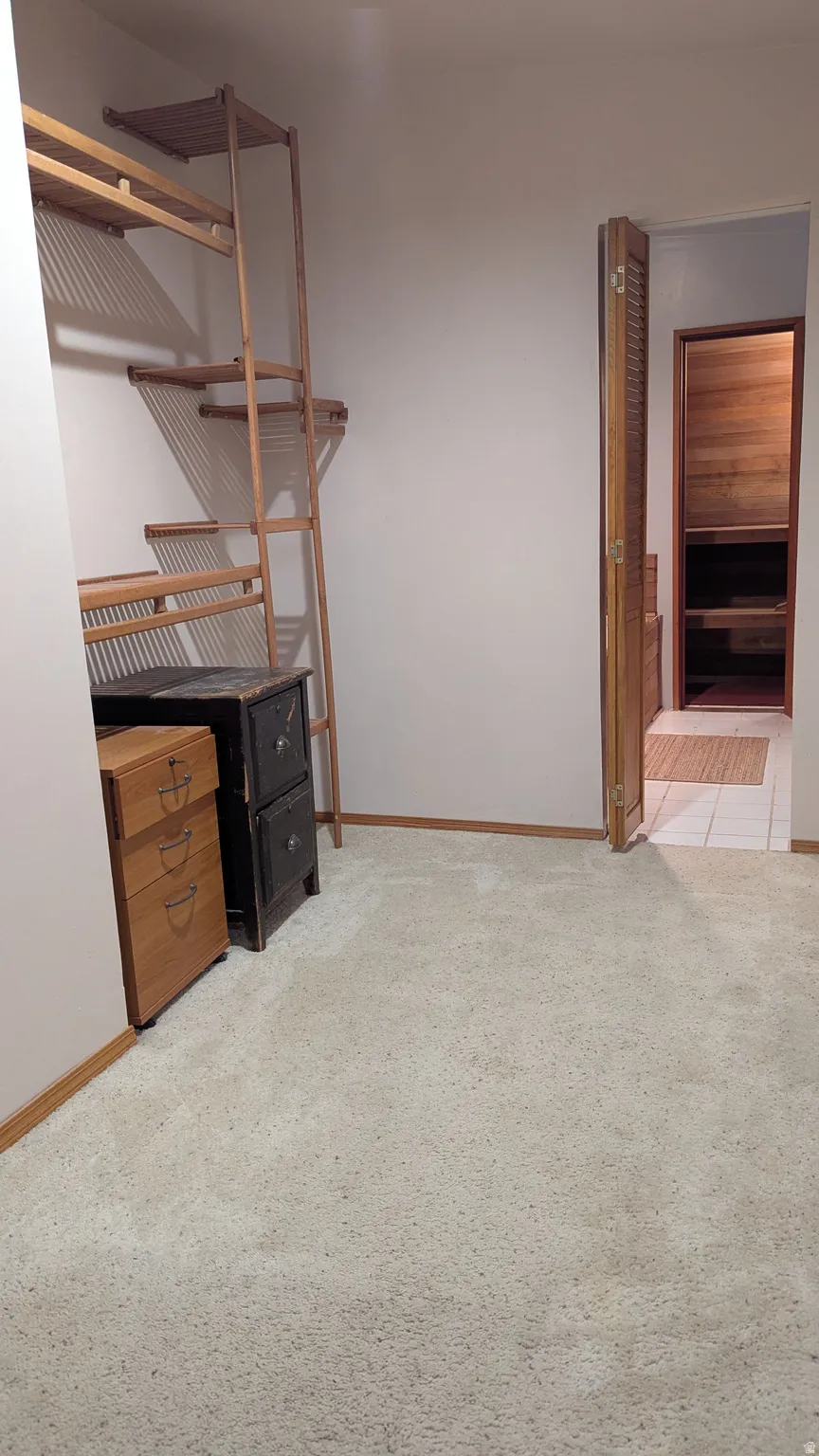 Wall-to-wall carpeting, wood baseboards, and built-in wood shelving system