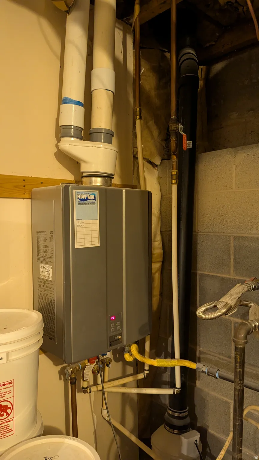 Wall-mounted tankless water heater with visible piping and utilities